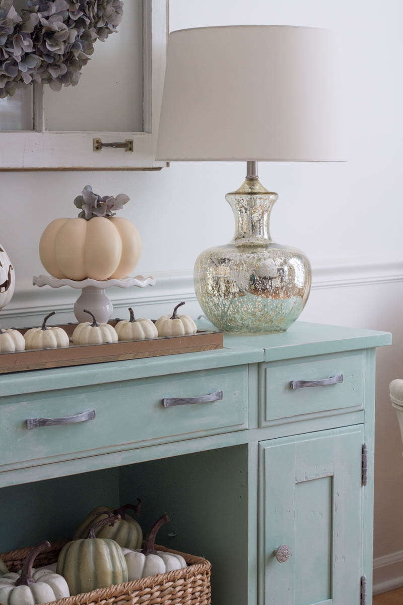 How to DIY a Neutral Farmhouse Decor for Fall - using paint from Amy Howard at Home, I transformed this sideboard into something rustic and gorgeous! The pumpkins, old window, and other various accents add a pop of fun to our living room while still keeping it soothing.